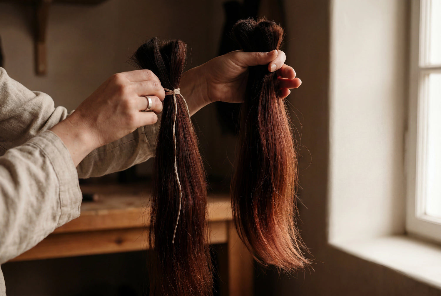 Stylist matching raw virgin hair extension samples to a client's natural hair shade at the consultation desk
