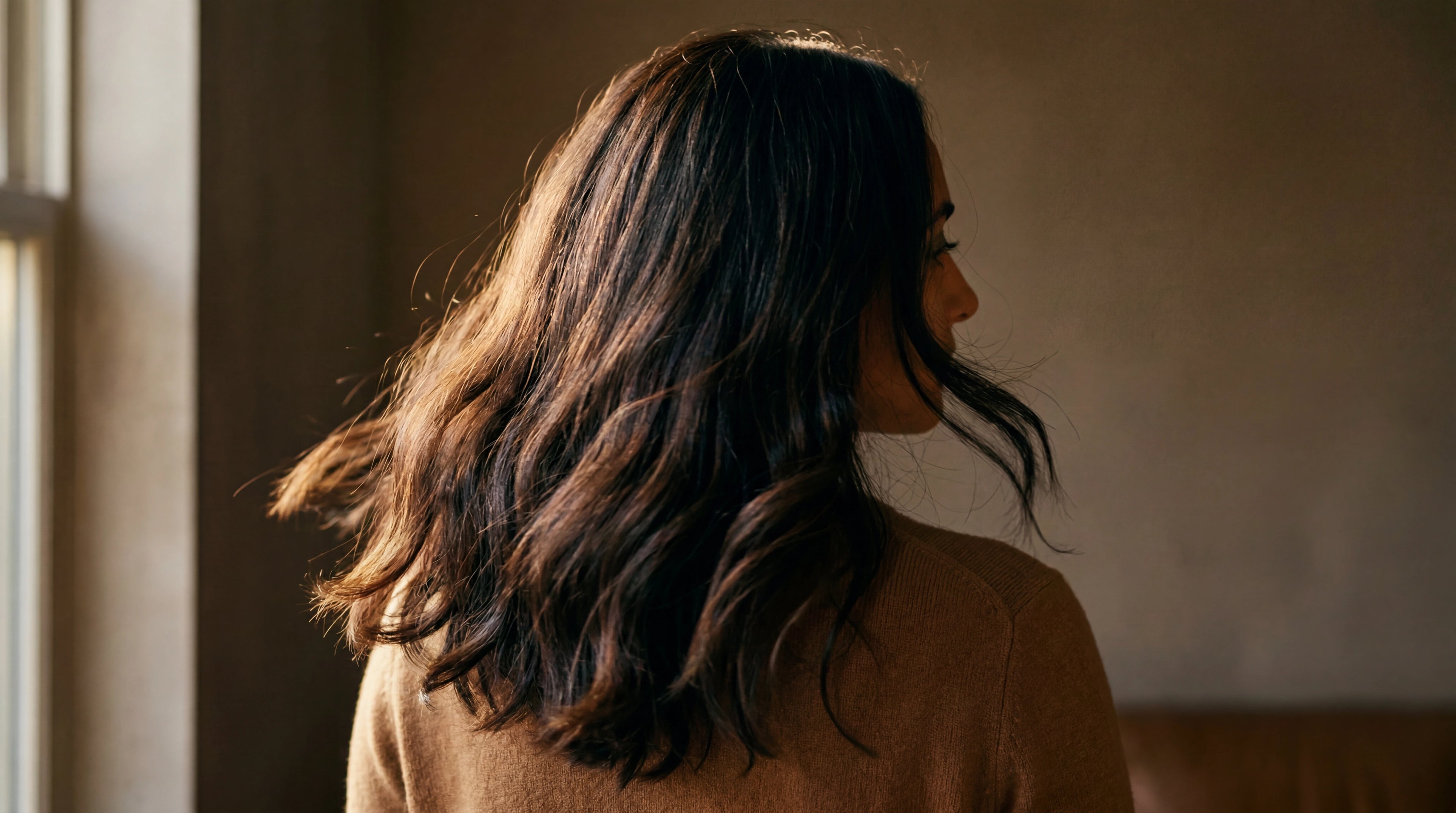 Editorial portrait of woman with raw virgin espresso brunette keratin-tip hair extensions from behind