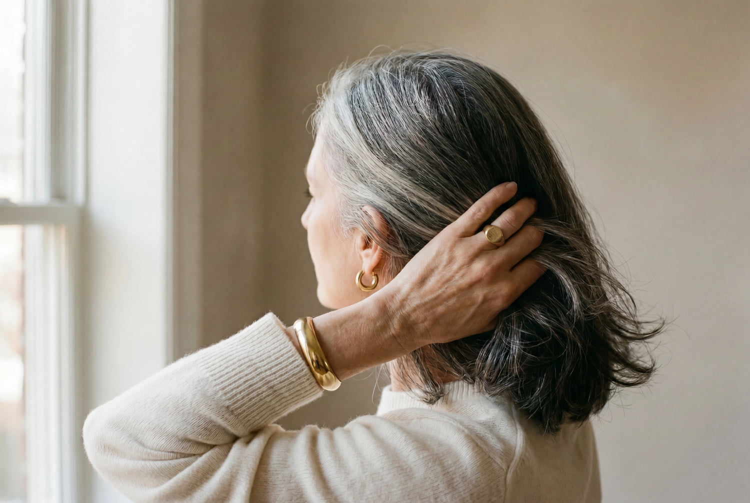Mature woman with raw virgin salt-and-pepper keratin-tip hair extensions in warm domestic light